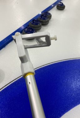 wheelchair curling | Neuromyelitis News | A 3D-printed tool is attached to the end of a stick, and can slip over the handle of a rock to allow a disabled curler to push it across the ice