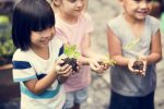 Discuss disability with child | Neuromyelitis News | Stock photo of three young children holding handfuls of soil with green sprouts.