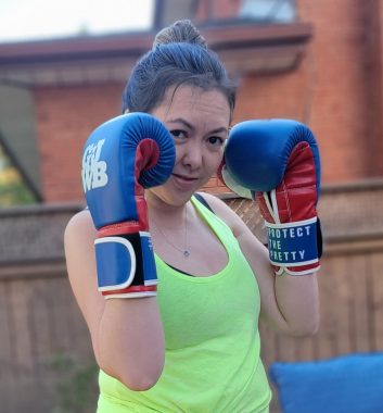 movement | Neuromyelitis News | Dressed in a lime green tank top and wearing big, blue boxing gloves, Jennifer looks at the camera while striking a defensive pose