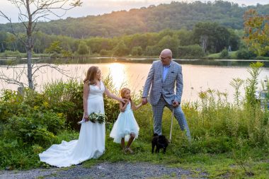 improve gut health | Neuromyelitis News | Jennifer and her husband, Mike, hold hands with their daughter, Sophie, in front of a lake. Jennifer is wearing a bridal gown and holding a bouquet of flowers, while Mike is wearing a suit.