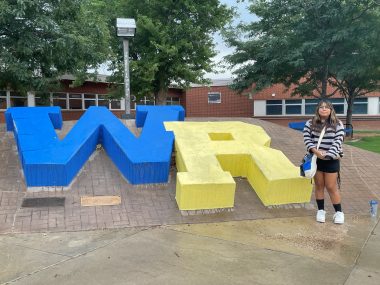neuromyelitis optica spectrum disorder | Neuromyelitis News | Bella, on her first day of high school, stands outdoors in front of a Blue "W" and yellow "R" presumably from the name of the high school